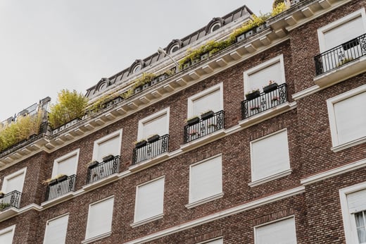 Moderno edificio comercial de ladrillo con contraventanas cerradas y balcones estructurados, que simboliza la estabilidad financiera y la confianza, valores fundamentales en los servicios de inteligencia crediticia.
