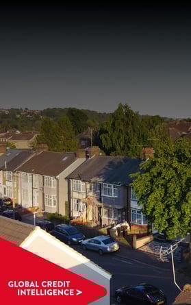 Vista aérea de un barrio suburbano bajo un cielo despejado, con una pancarta roja superpuesta en la que se lee "Global Credit Intelligence", que representa información sobre los mercados inmobiliario y crediticio.