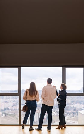 Un agente inmobiliario muestra a una pareja las vistas de una posible casa.