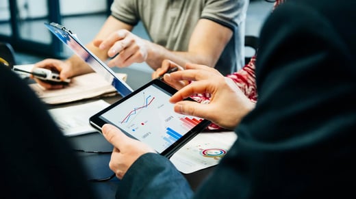 Equipo de empresarios revisando los análisis en una tableta y un gráfico.